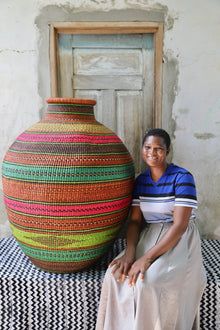 a woman sitting next to a large woven vase