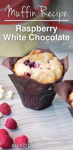 raspberry white chocolate muffin in a wrapper on a table with berries