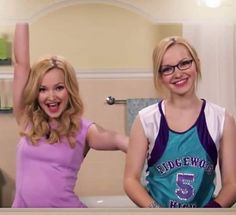 two women standing next to each other in front of a bathroom mirror with their arms up