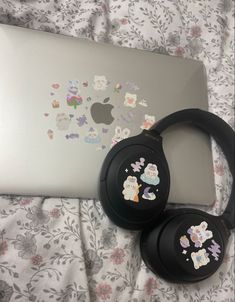 two black headphones sitting next to an apple laptop on top of a floral blanket