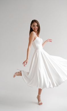 a woman in a white dress is posing for the camera