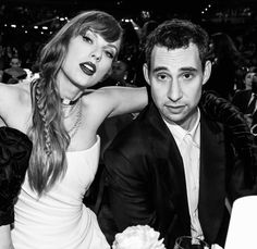 a man and woman sitting next to each other in front of a table full of people