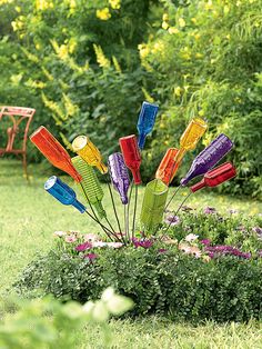 there is a colorful sculpture in the middle of some grass and flowers on the ground