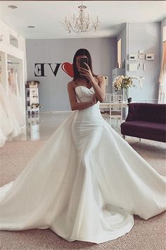 a woman taking a selfie in front of a mirror wearing a white wedding dress