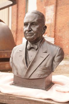 a statue of a man wearing a suit and bow tie sitting on top of a table