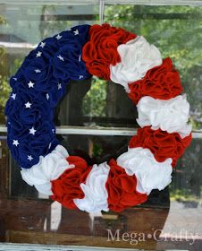 a wreath with red, white and blue flowers is hanging on a window sill