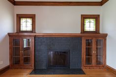 an empty living room with a fireplace and stained glass windows on the top ledges