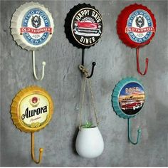 there are five different types of beer bottle caps hanging from hooks on the wall,