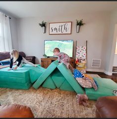 two children are playing on inflatable couches while another child is watching television