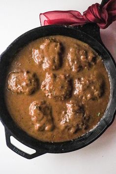 meatballs and gravy in a skillet with a red bow on the side