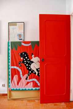 an open red door with a painting on it