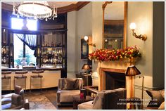 a living room filled with furniture and a fire place under a chandelier next to a bar