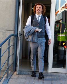 a man wearing a suit and tie walking out of a building with his hand in his pocket