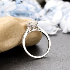 a diamond ring sitting on top of a rock next to a pile of cloths