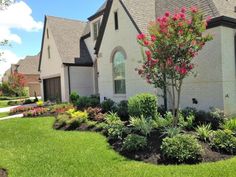 a house with landscaping in front of it and flowers on the lawn next to it