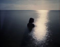 a person standing in the water with their back to the camera and looking at the ocean