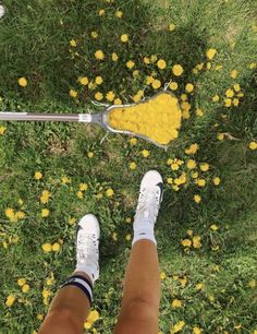 a person standing in the grass with their legs crossed and tennis racket resting on top of them