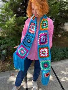 a woman with red hair wearing a blue crocheted shawl and pink shirt