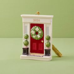 a small christmas ornament with a wreath on the door and potted plants