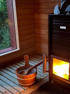 a wood burning stove inside of a wooden room next to a large window with an open door