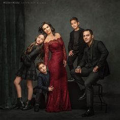 a family posing for a photo in front of a dark background, with one child and two adults