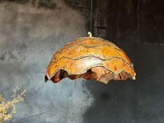 a wooden lamp hanging from a ceiling in front of a gray wall with yellow flowers