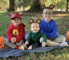 three children wearing mouse ears sitting on a blanket