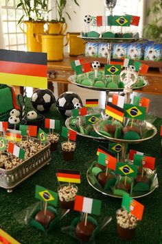 a table topped with lots of desserts covered in green and red flags on top of grass