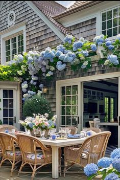 an outdoor dining area with blue hydrangeas and wicker chairs