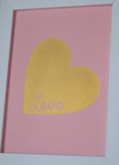 a pink and gold framed heart with the word love on it's back side