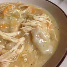 a bowl filled with chicken and dumplings on top of a white tablecloth covered table