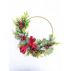 a christmas wreath with holly and red ribbon hanging on a wall next to a cake