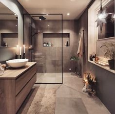 a bathroom with a glass shower door, sink and large mirror on the wall next to it