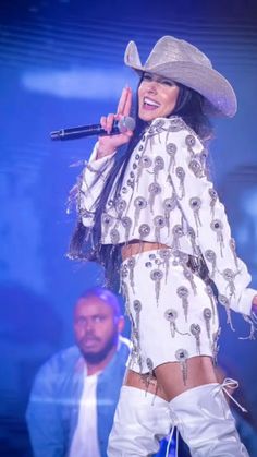 a woman in white outfit and cowboy hat on stage