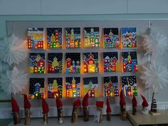 christmas decorations are displayed on a wall with paper snowflakes and santa's hats