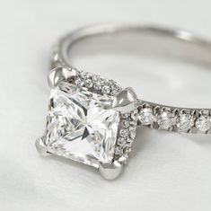 an engagement ring with a princess cut diamond and pave set diamonds on the band