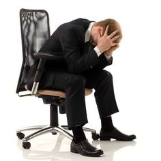 a man sitting in an office chair with his head in his hands