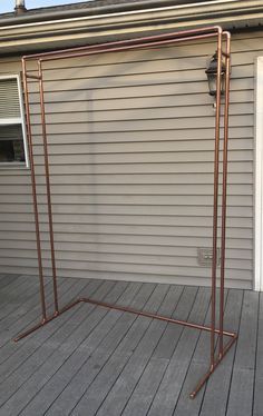 a metal rack on a wooden deck next to a building with a door and window