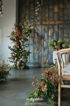 a room filled with lots of flowers next to a wooden door covered in greenery