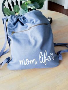 This mom life draw Sting Canvas Bag Is everything! It is Huge and perfect for fitting all your mama aka kids essentials Perfect for running out throwing snacks, wallet and diaper on the go instead of lugging that huge diaper bag around. 17 inches Long 14 1/4 inches wide 14.0 oz., 100% cotton Large main compartment Front zippered pocket with antique brass zipper Webbing straps Available in Black and Blue FOLLOW US ON SOCIAL MEDIA: Instagram: @righthereathome Facebook: @righthereathome Connect wit Backpack Gym Bag With Removable Pouch, Everyday Gym Backpack With Removable Pouch, Back To School Tote Backpack, Mother's Day Gift Bag For Travel, Everyday Backpack With Dust Bag Included, Blue Backpack With Dust Bag For Everyday Use, Large Capacity Backpack Bags For Gifts, Large Capacity Backpack Bags As Gifts, Large Capacity Backpack For Gifts