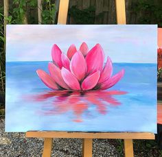 a pink flower sitting on top of a painting easel