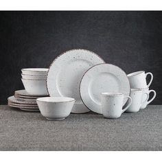 a stack of white dishes sitting next to each other on top of a gray surface