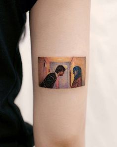 a woman's arm with a tattoo on it that has an image of two people looking at each other