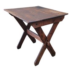 an old wooden table with two crossed legs