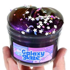 a hand holding a container filled with purple and white stars