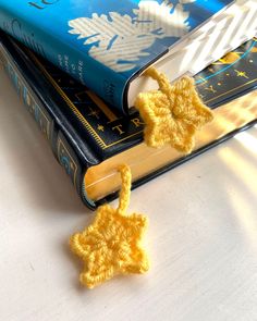 two crocheted bookmarks are sitting on top of each other next to a blue book