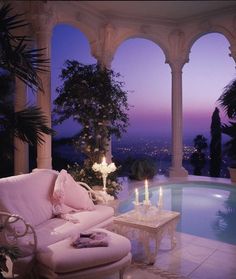 a living room with a couch and candles in the corner near an outdoor swimming pool