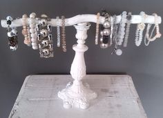 a white jewelry rack with bracelets and necklaces hanging from it's sides