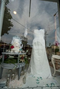 a wedding dress is displayed in a shop window with other items on display behind it