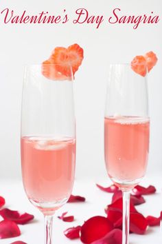 two wine glasses filled with pink liquid and garnished with rose petals on a white surface